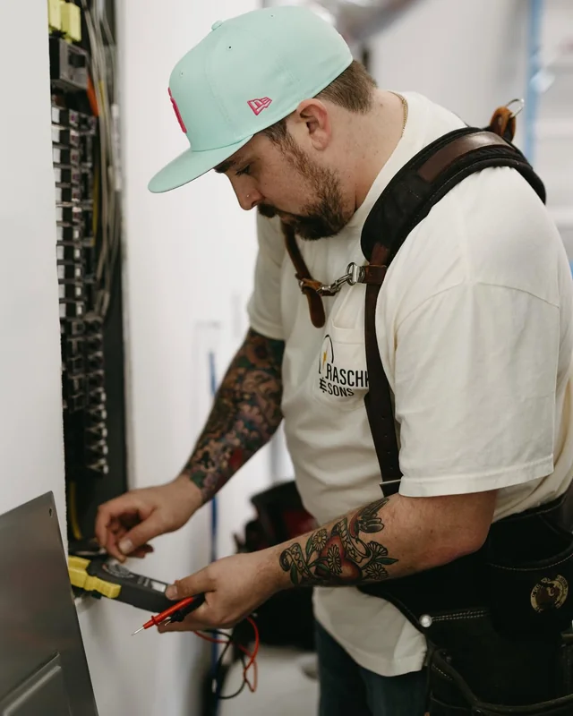 An electrician from Raschke & Sons working on a home's electrical panel