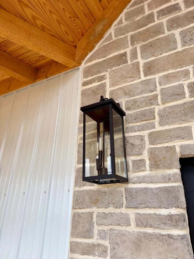 Black lantern mounted on a brick porch beneath a wood ceiling